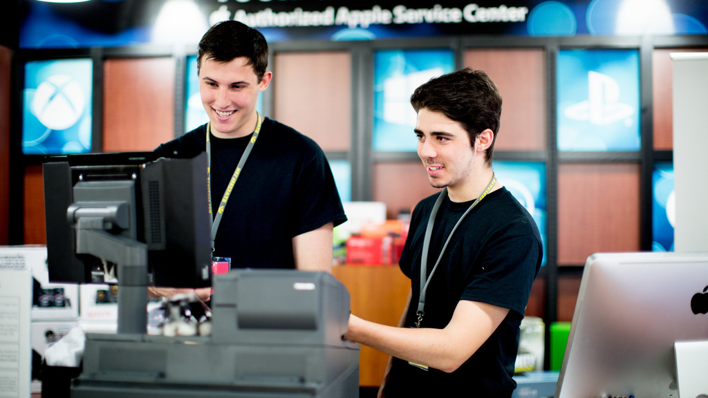 two students standing behind cash register